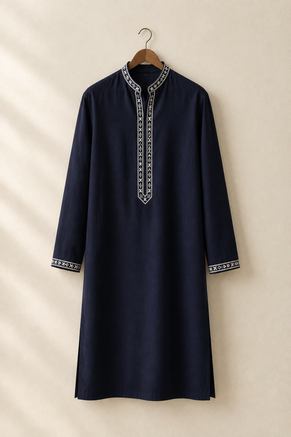 Deep navy embroidered kurta hanging on a wooden hanger against a warm studio wall